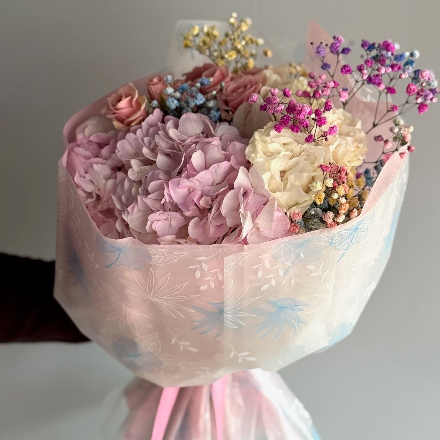 Bouquet of pink and white flowers with ribbons on a neutral background