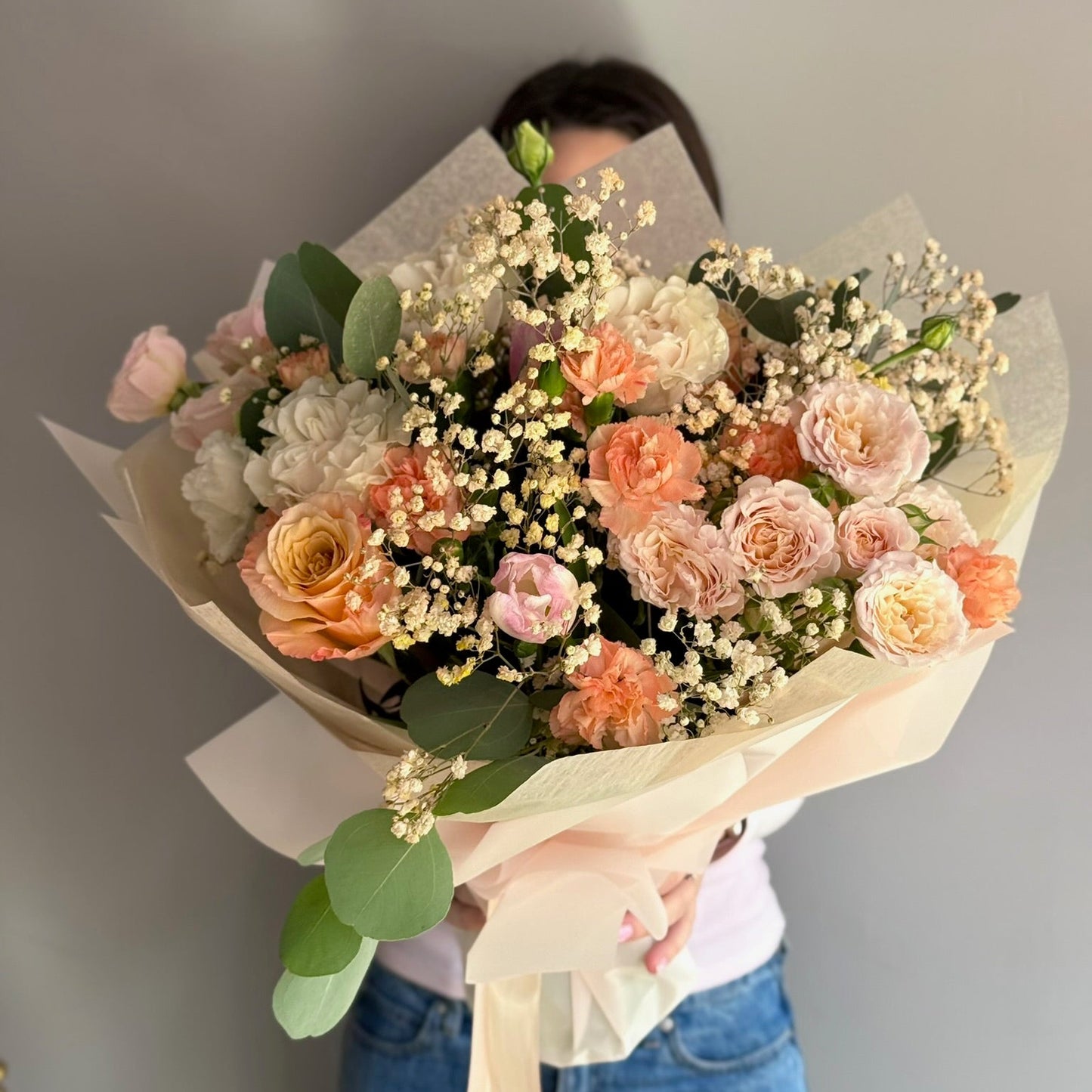 Person holding a bouquet of flowers against a plain background