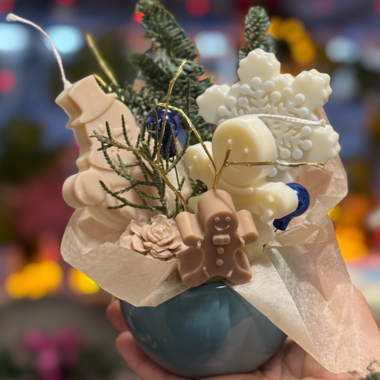Decorative candle holder with Christmas-themed elements including a snowman, gingerbread man, and tree branches.