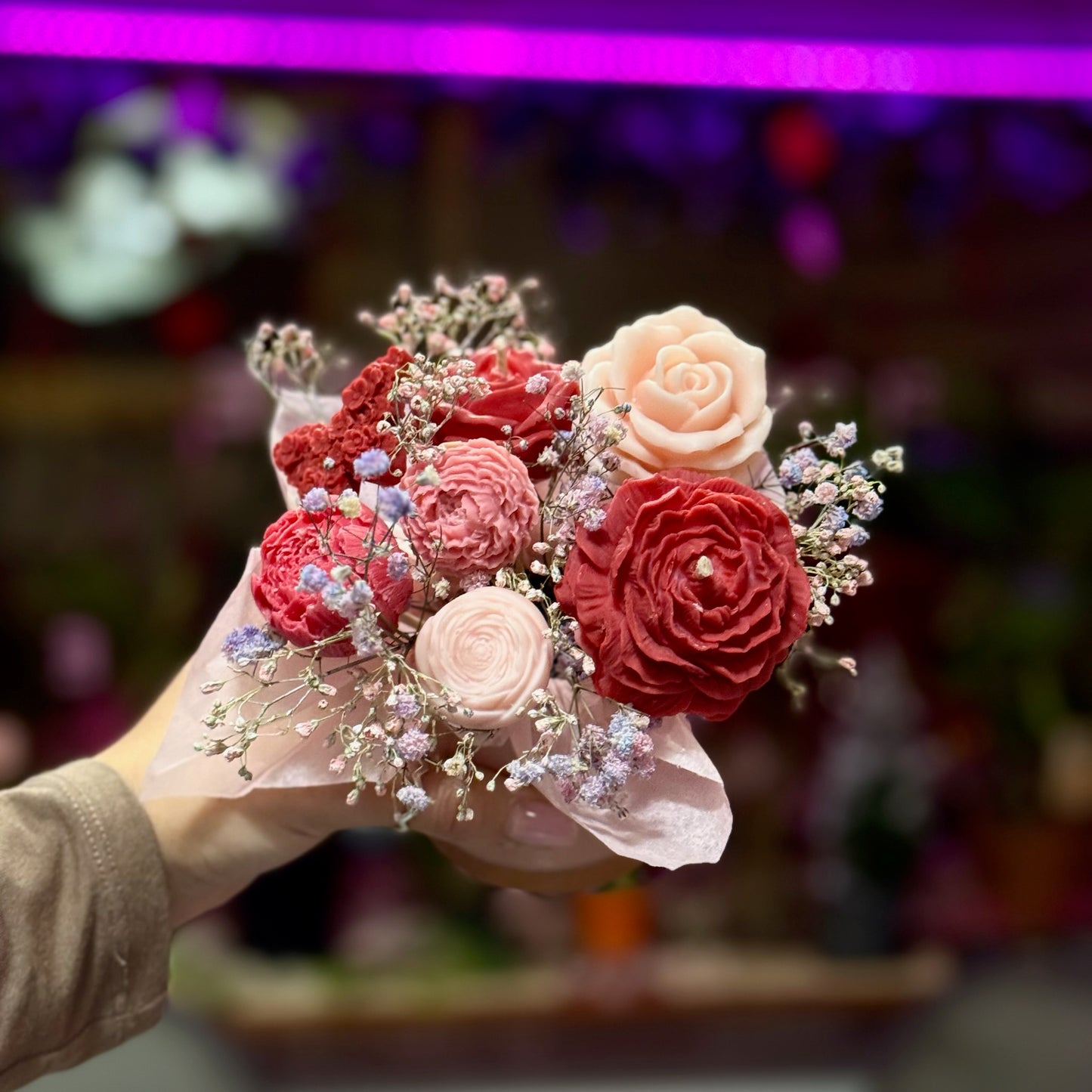 Bouquet of red and pink flowers held by a person with a blurred background