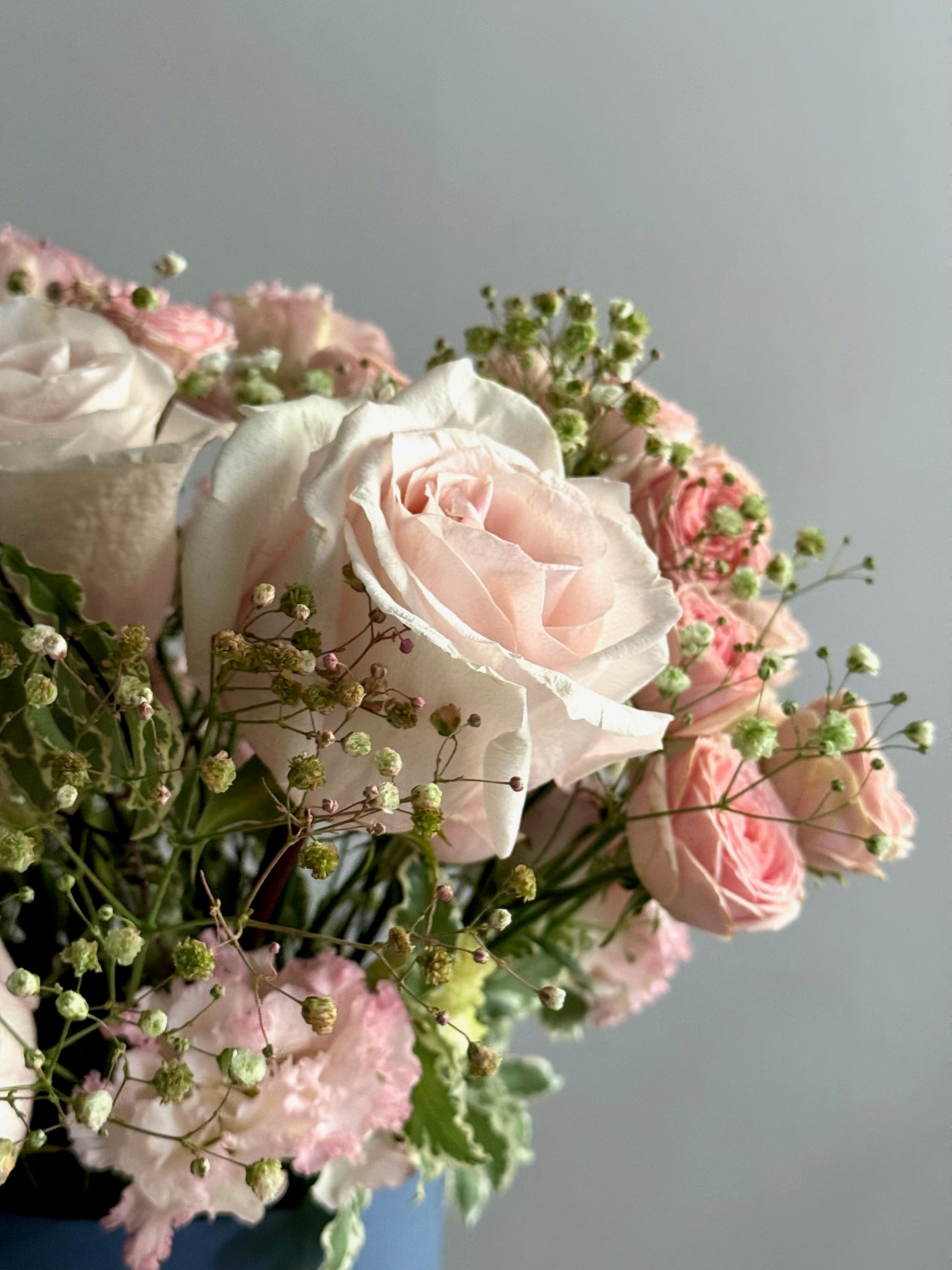 Bouquet of pink and white flowers with greenery on a light gray background