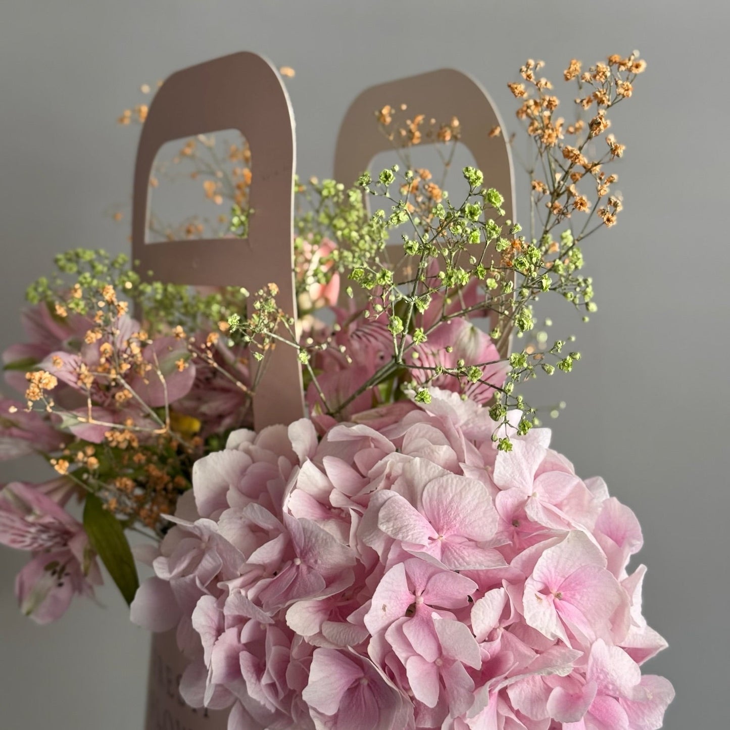 Aranjament în pungă roz cu flori în nuanțe vibrante de piersică, Roses & More