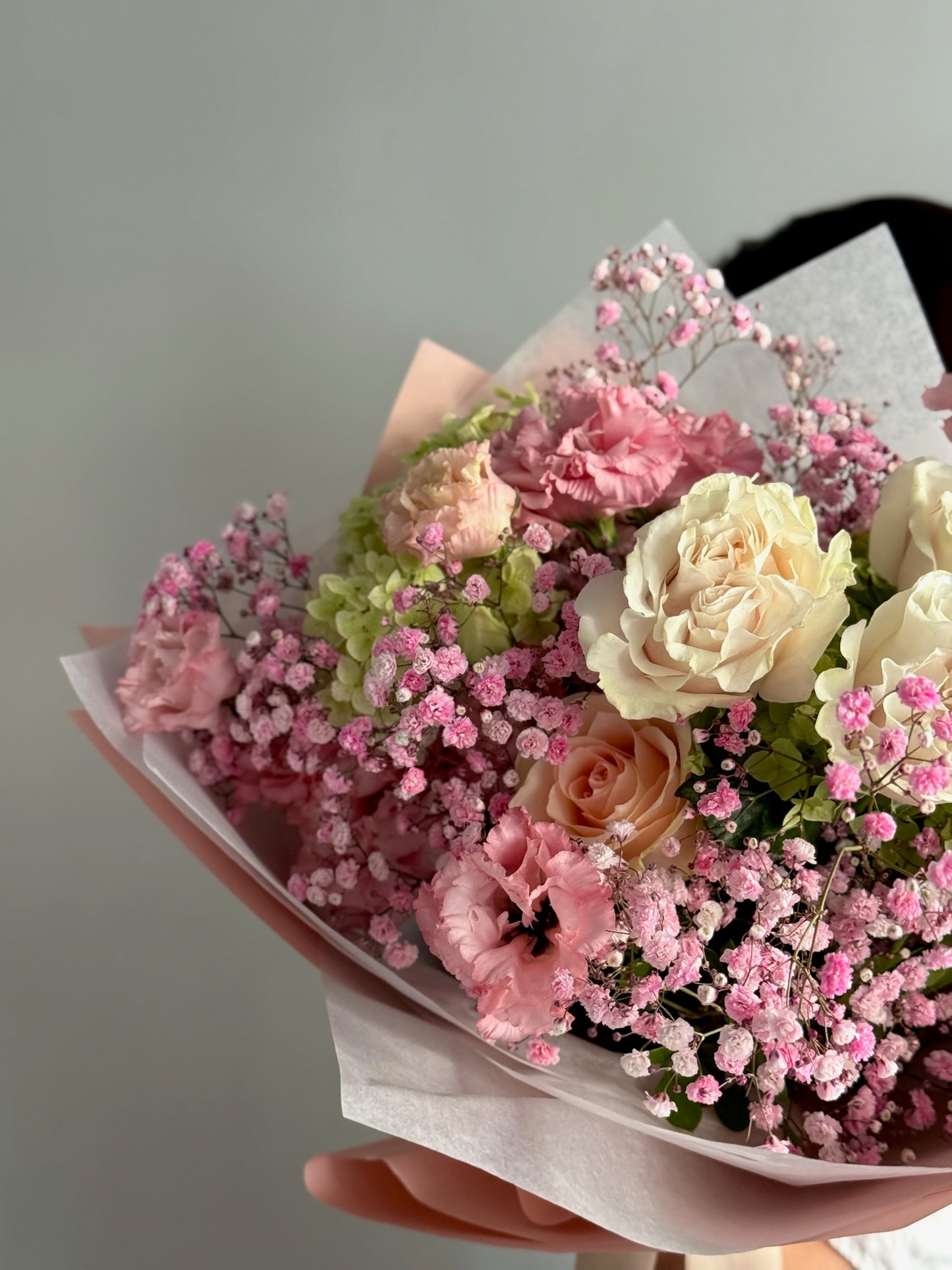 Bouquet of pink and white flowers held against a neutral background
