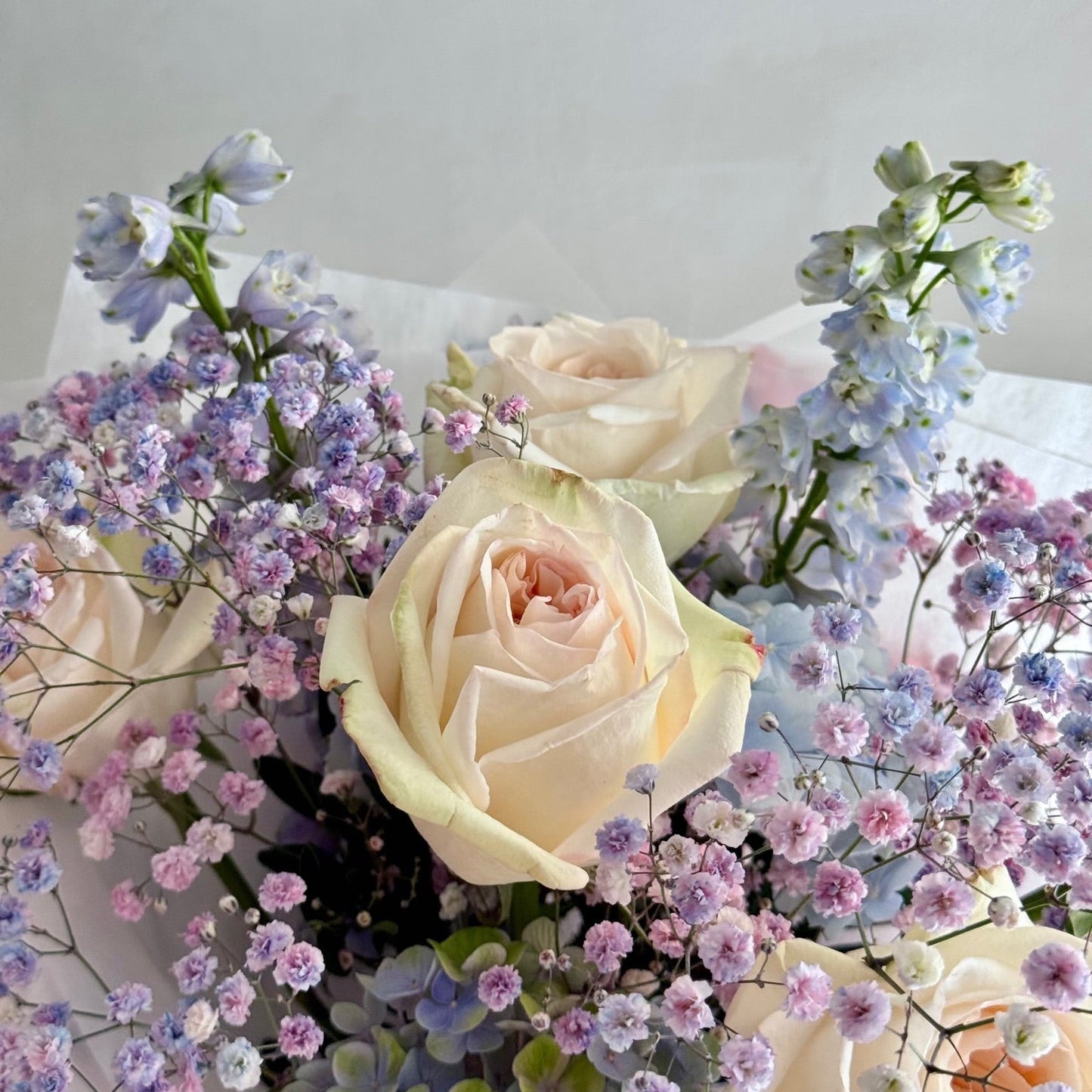 Bouquet of white and pastel-colored flowers on a light gray background