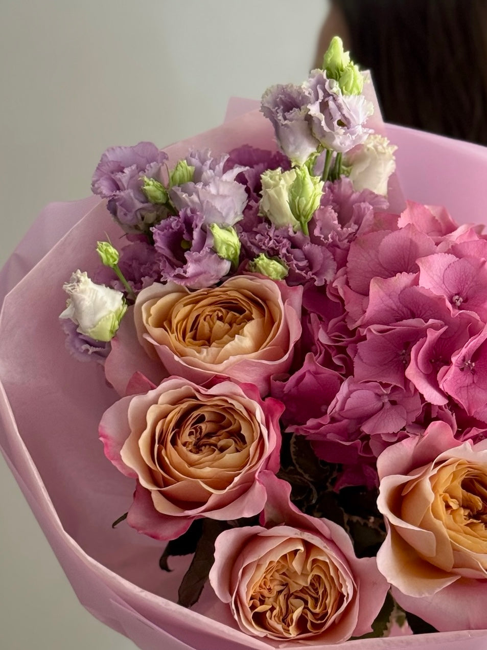 Bouquet of flowers with pink, purple, and beige colors in a pink wrap.