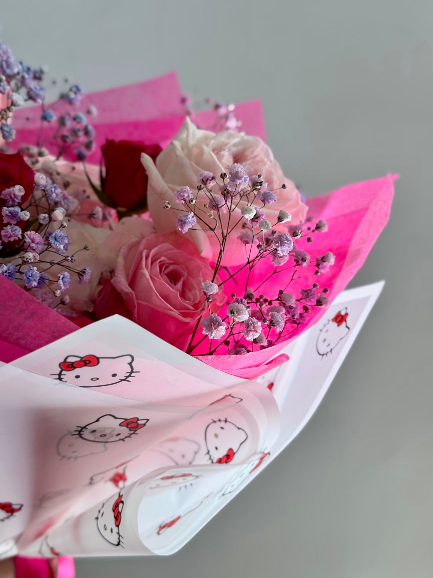 Bouquet of pink roses with baby's breath on pink tissue paper with Hello Kitty design.