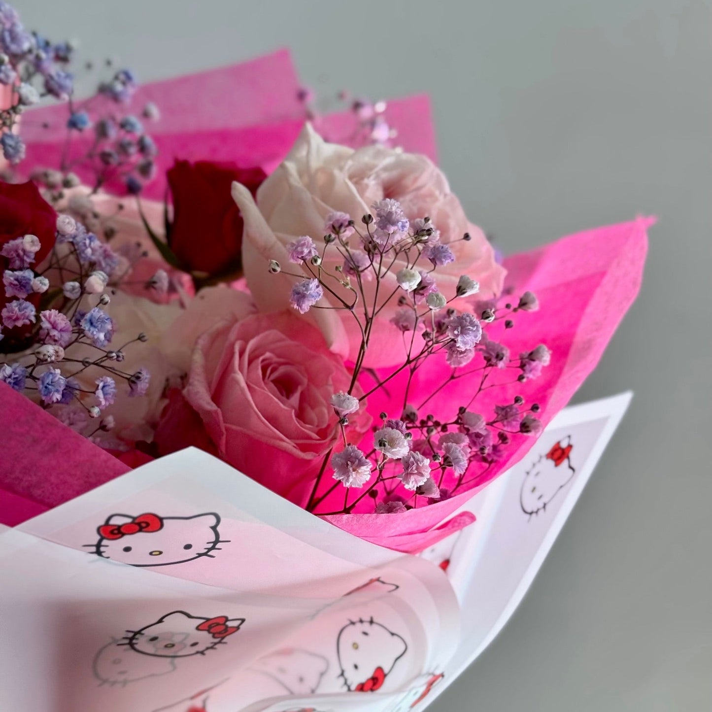 Bouquet of pink roses with baby's breath on pink tissue paper with Hello Kitty design.