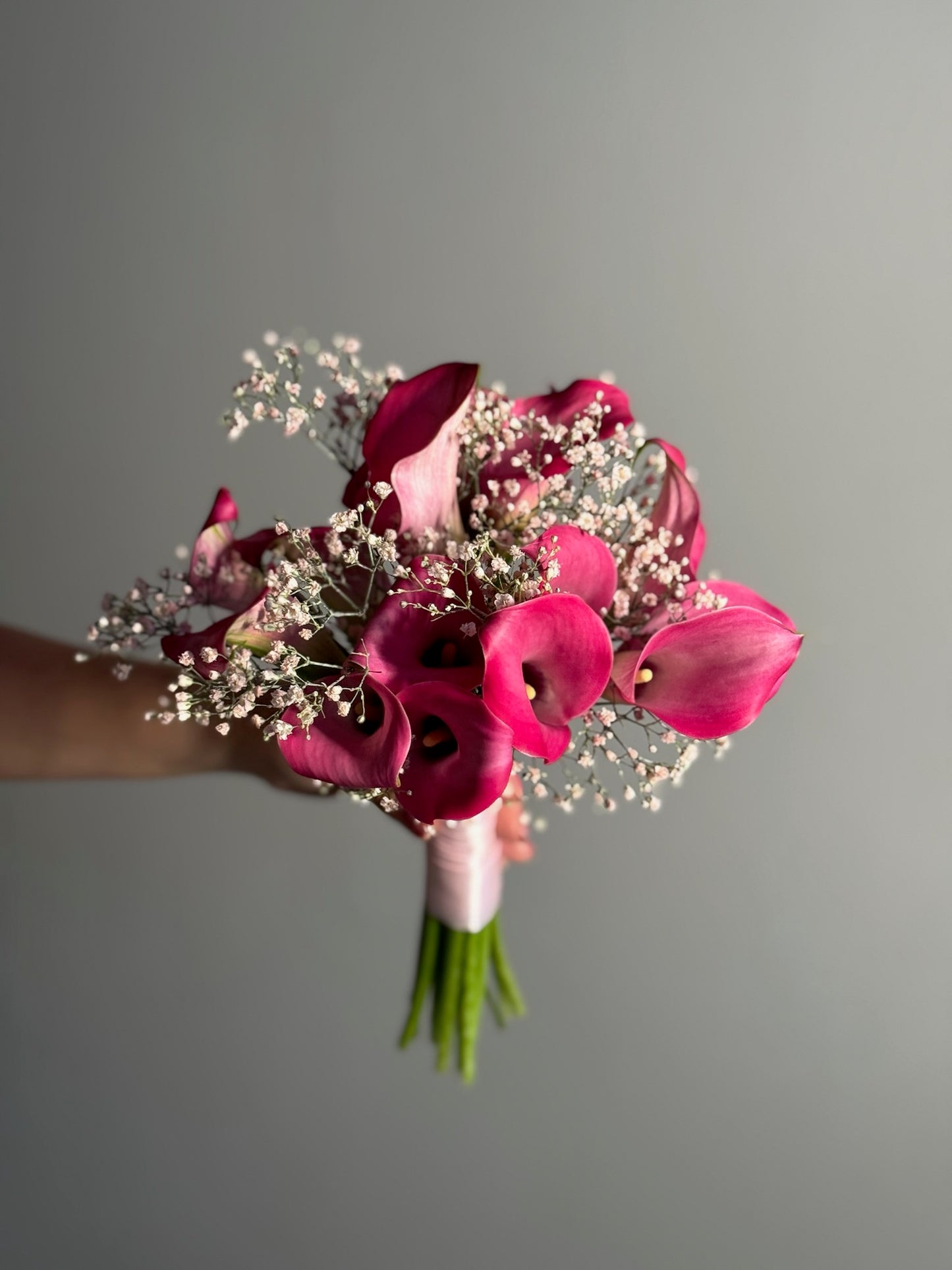 Bouquet of pink flowers held against a gray background