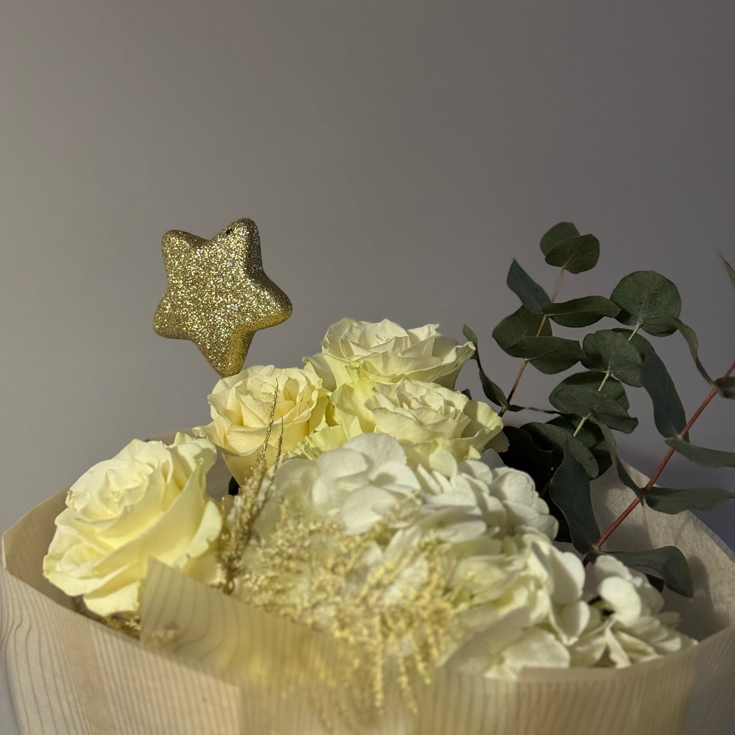 Bouquet of yellow flowers with a gold star-shaped decoration on a gray background