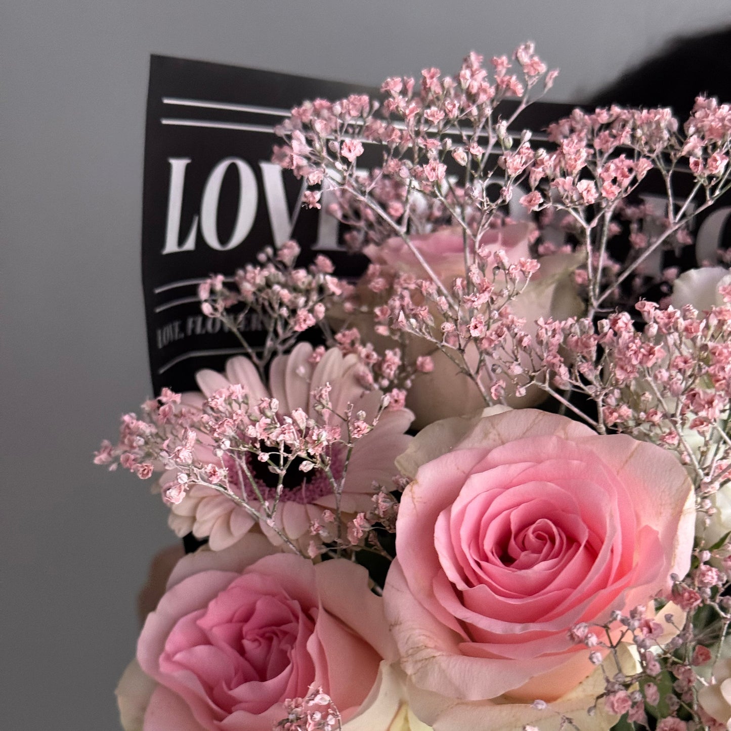 Bouquet of pink and white roses with baby's breath on a black background with 'LOVE' text.