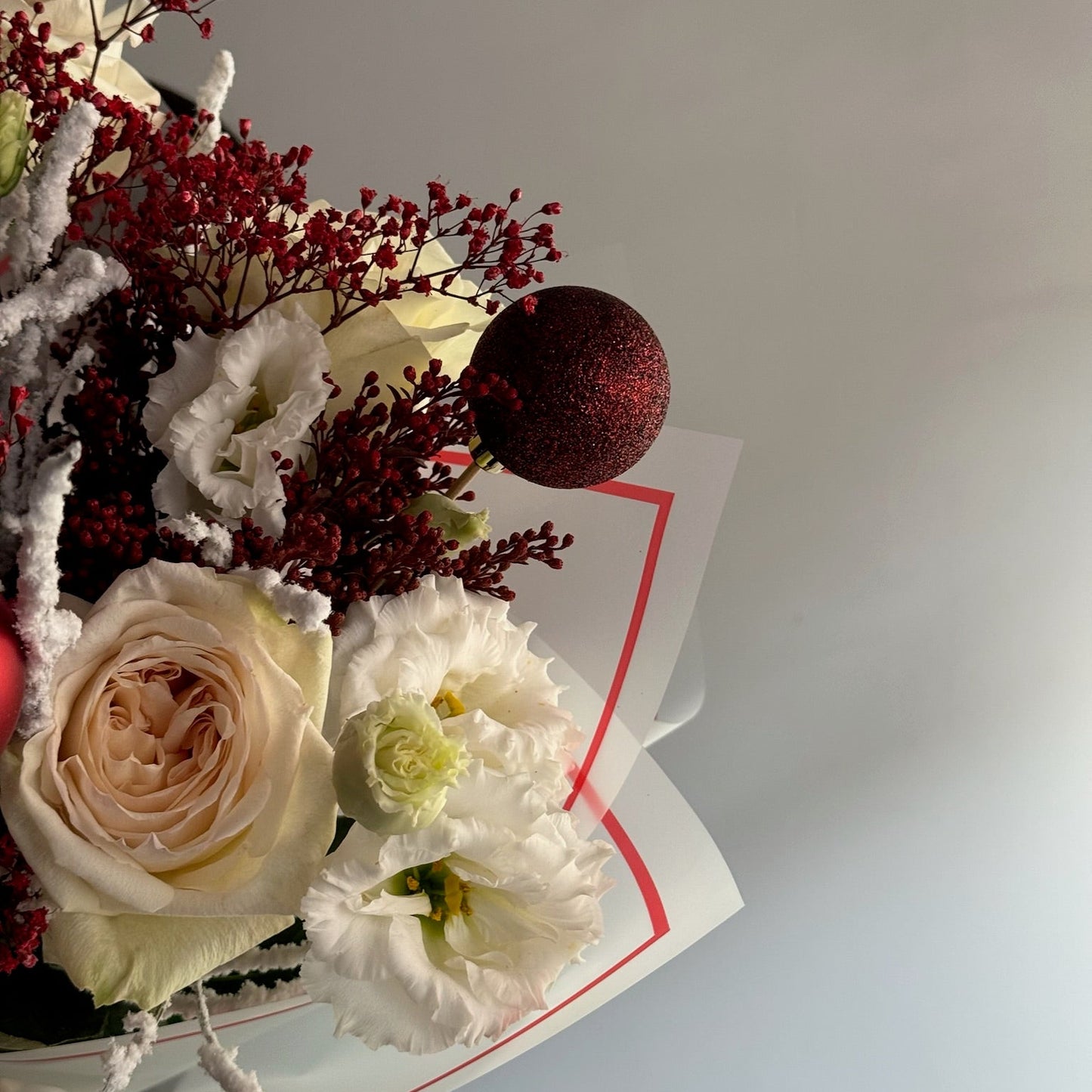 Bouquet of flowers with a decorative red ball on a light gray background