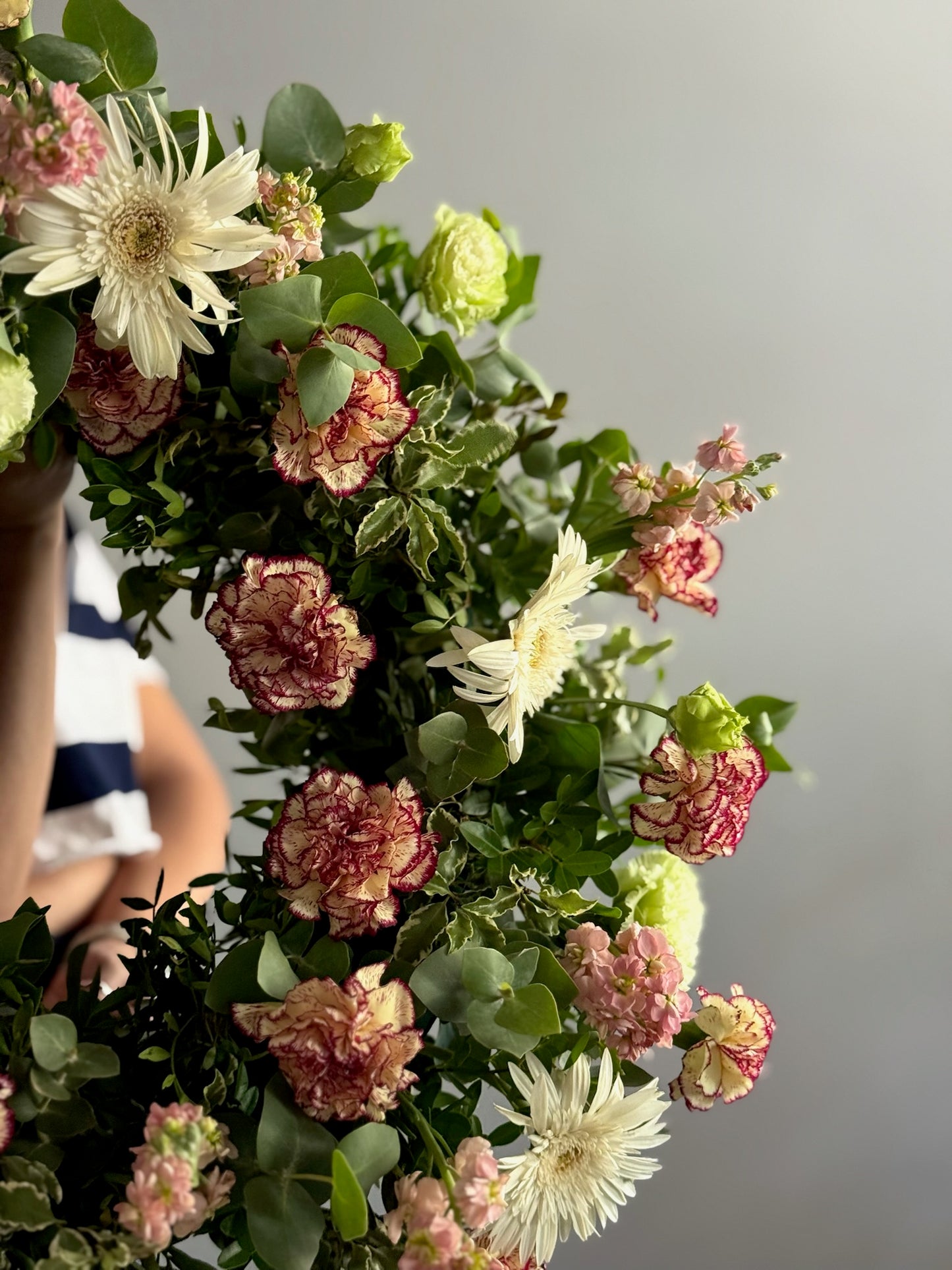 Coroana funerară of flowers with a blurred person in the background