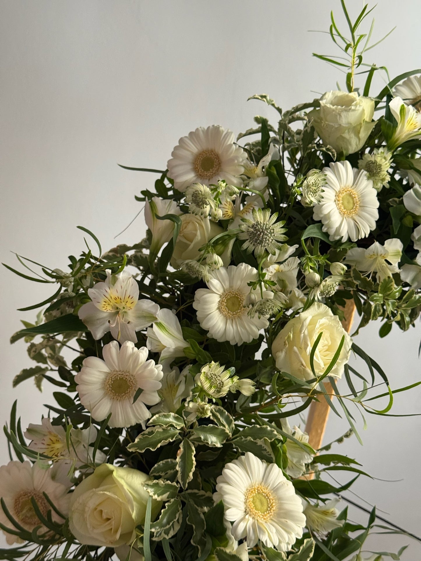 Bouquet of white and green flowers with greenery on a light gray background