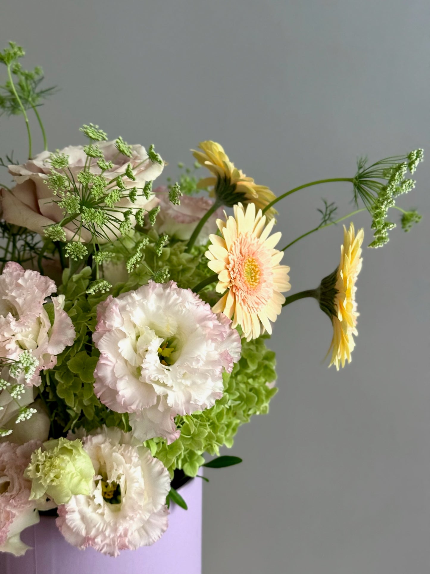 Bouquet of flowers including pink and white carnations and yellow gerberas on a gray background