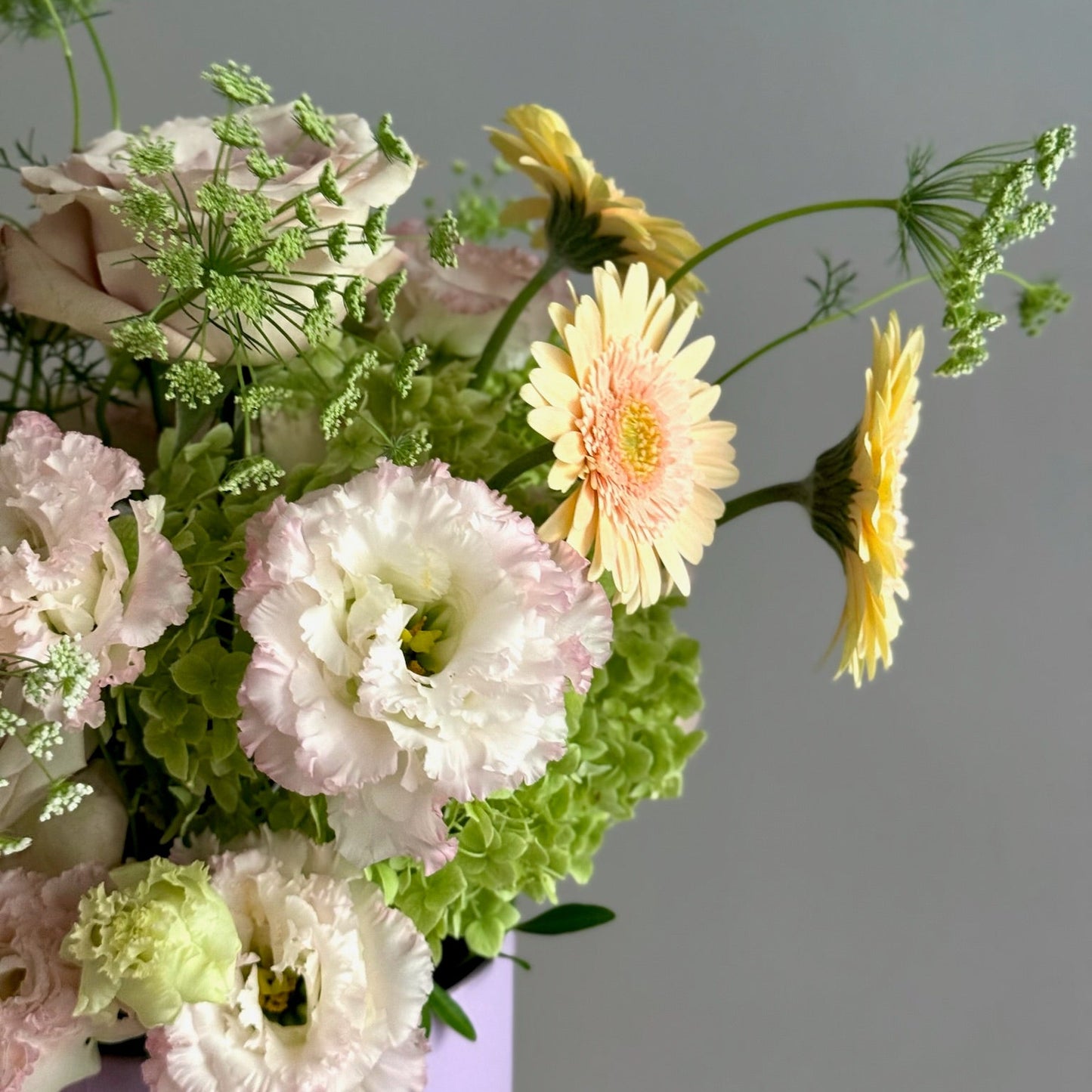 Bouquet of flowers including pink and white carnations and yellow gerberas on a gray background