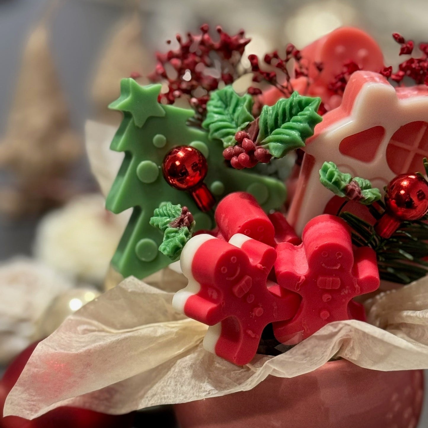 Decorative Christmas-themed soaps with gingerbread men, holly leaves, and stars on a pink soap base.