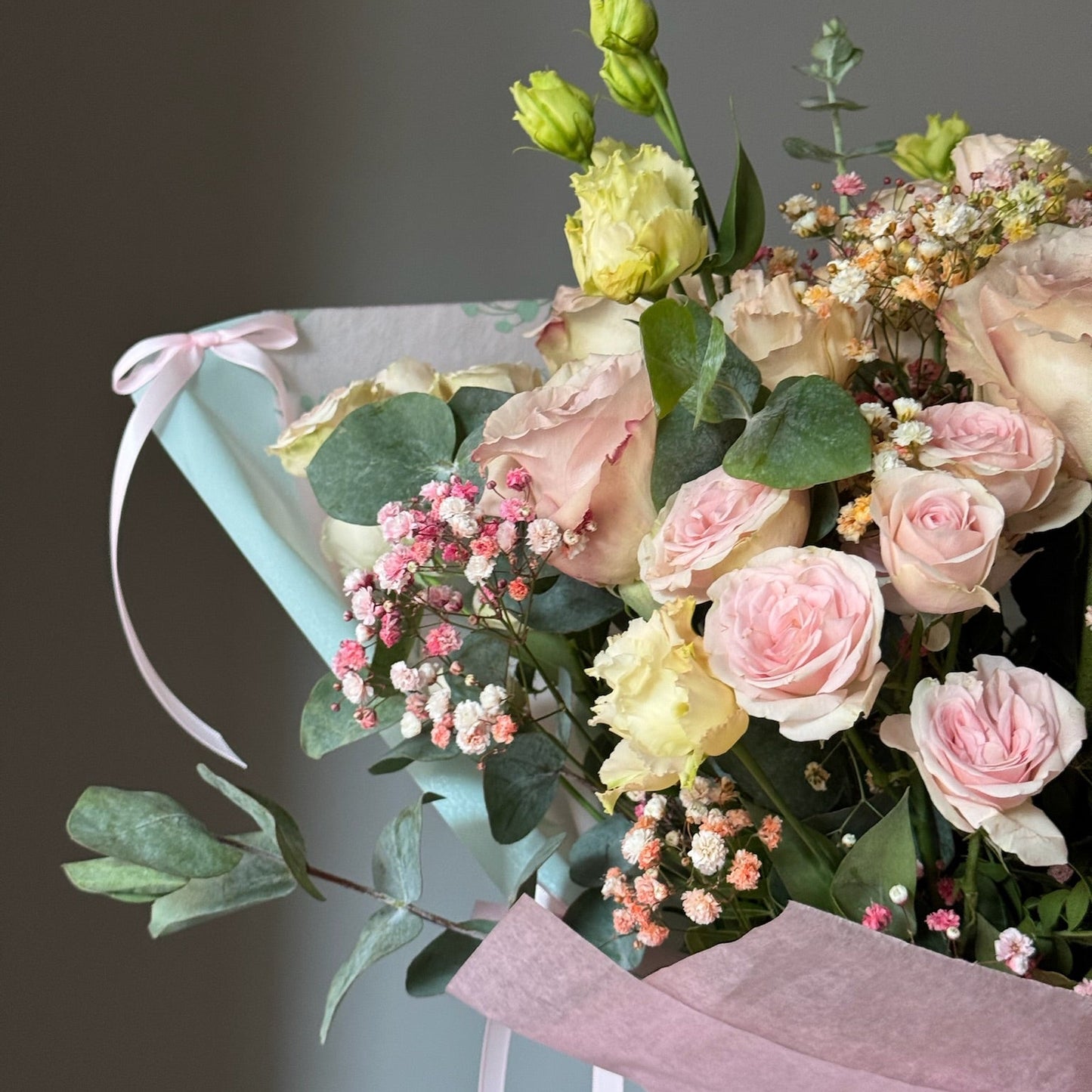 Pink flowers in beui wrapping paper on grey background