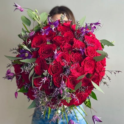 Person holding a big red bouquet on grey background 
