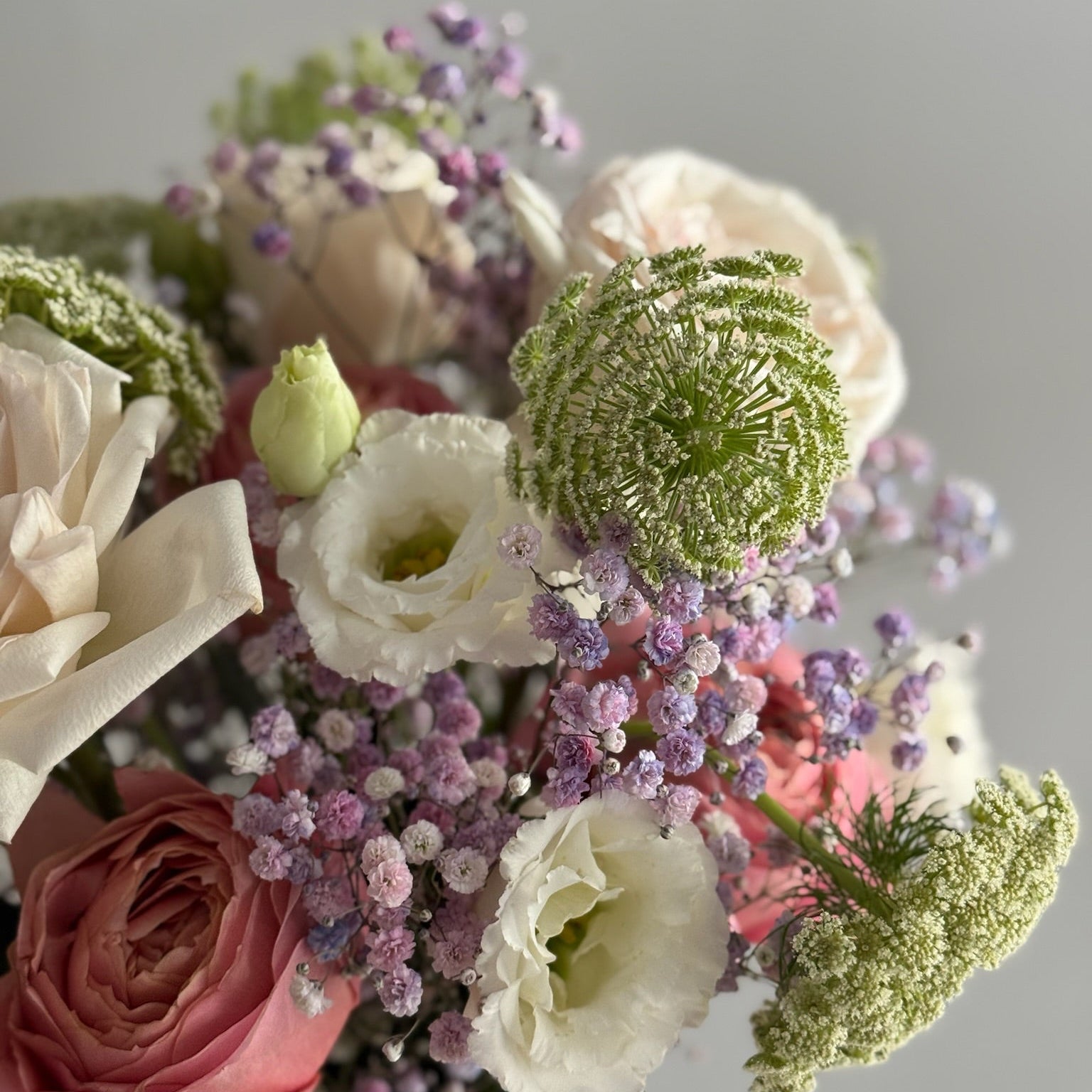 Bouquet of flowers with pink, white, and green colors on a light gray background