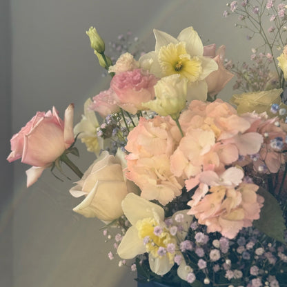 Bouquet of pastel flowers in a blue container against a gray background