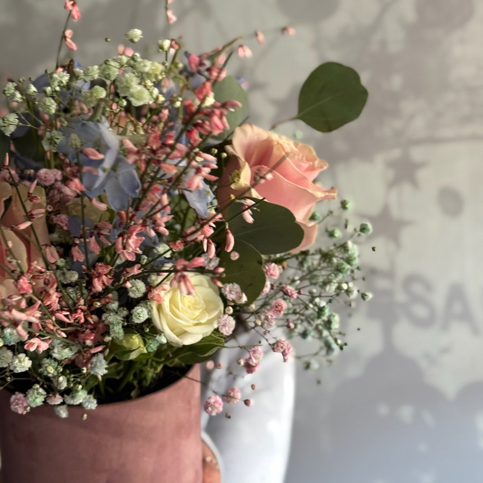 Bouquet of flowers with greenery in a pot against a neutral background