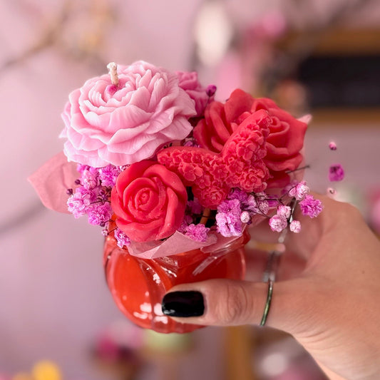 Little candle arrangement held by a person on pink background 