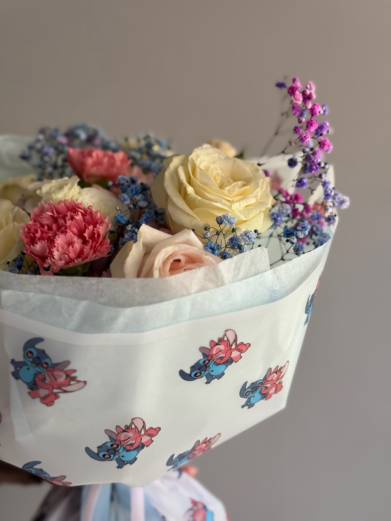 Bouquet of flowers held by a person against a plain background