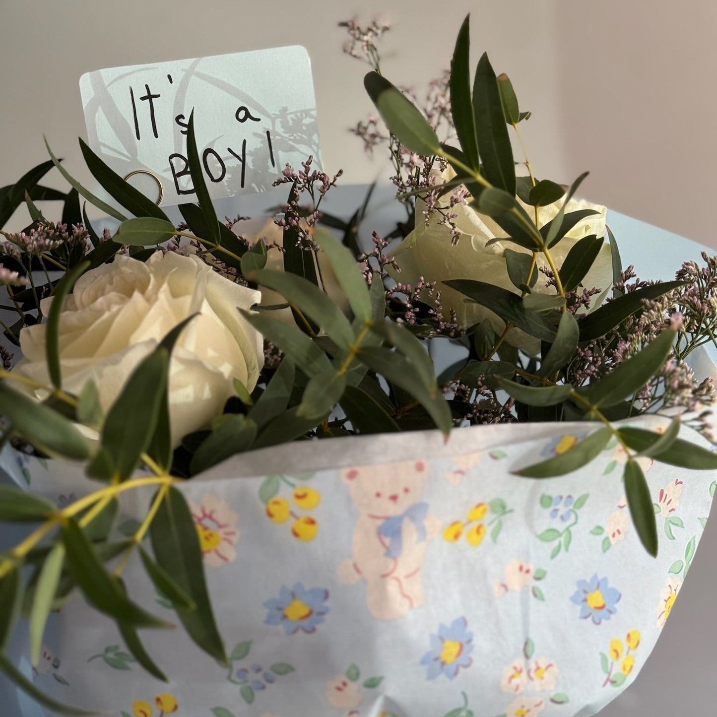 Floral arrangement with a 'It's a Boy!' card on a floral-patterned paper.