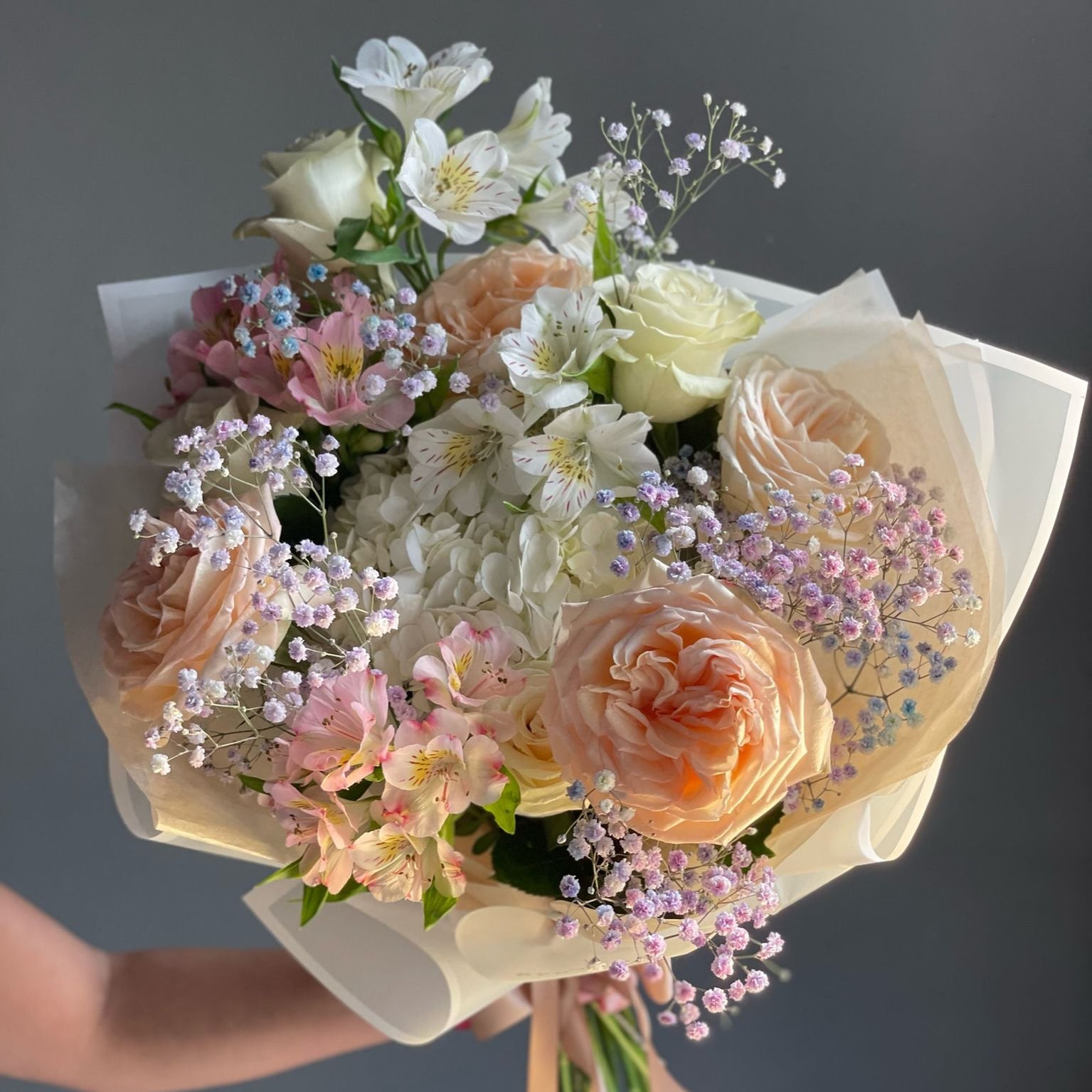Bouquet of flowers held by a person against a dark background