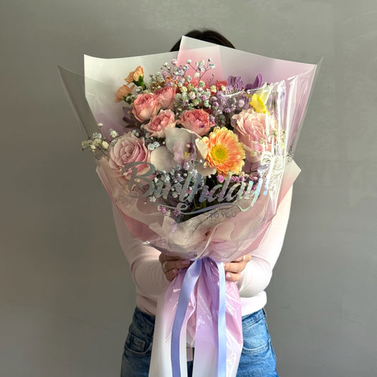Person holding a colorful floral bouquet on  grey background 