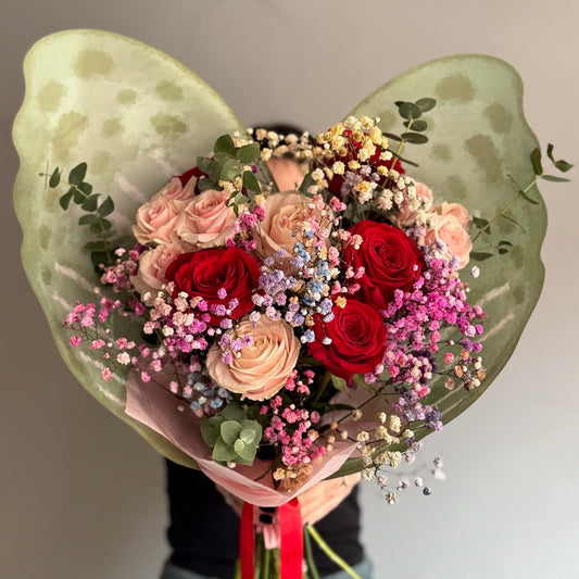 Bouquet of flowers with a butterfly-shaped green wrap on a plain background