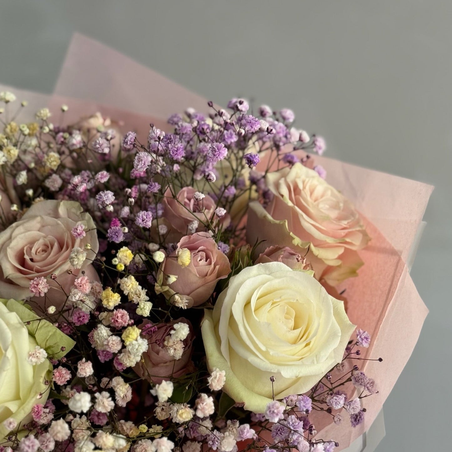 Bouquet of pink, white, and beige roses with small lilac flowers