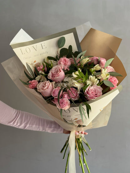Bouquet with white and pink flowers with wrapping paper on grey background 