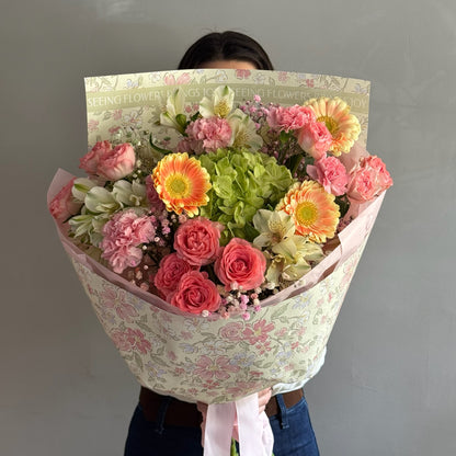 Colorful bouquet with mix of flowers and wrapping paper held on grey background 