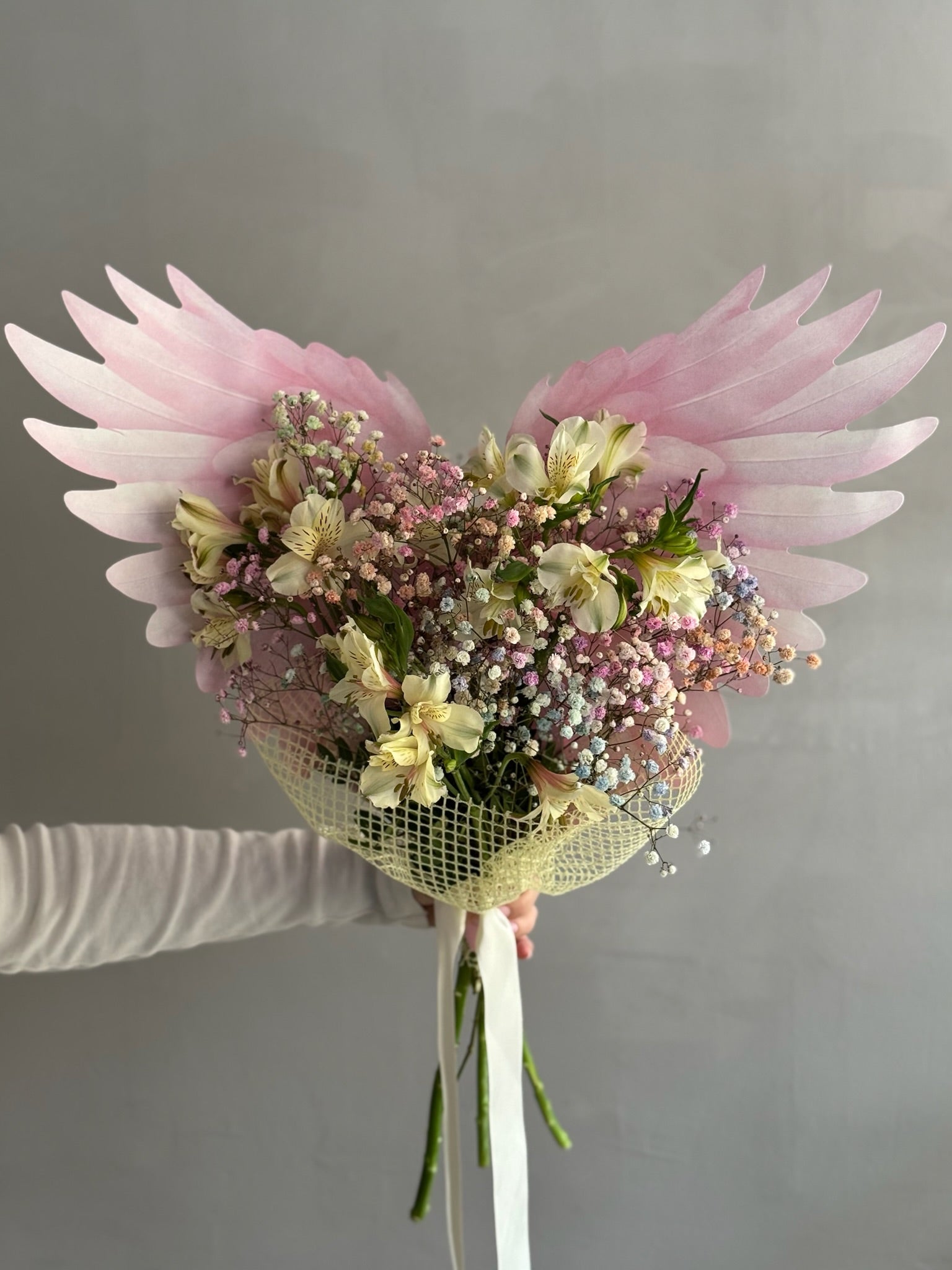 Pink Bouquet with butterfly wrapping paper held on grey background 