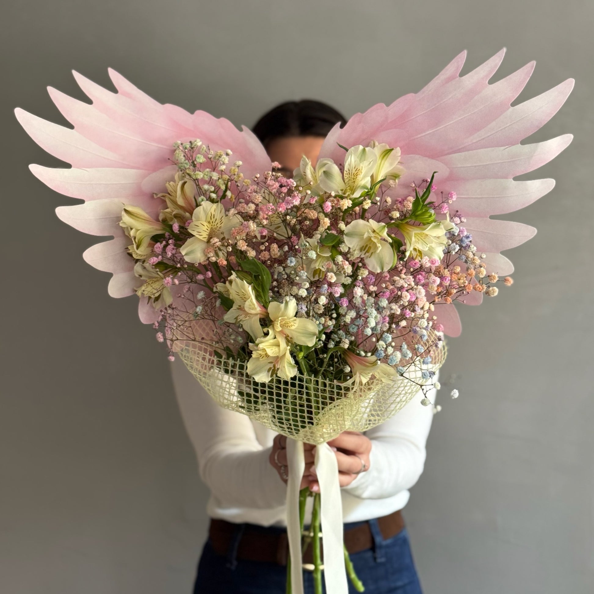 Bouquet of flowers with butterfly wrapping paper held by person on grey background 