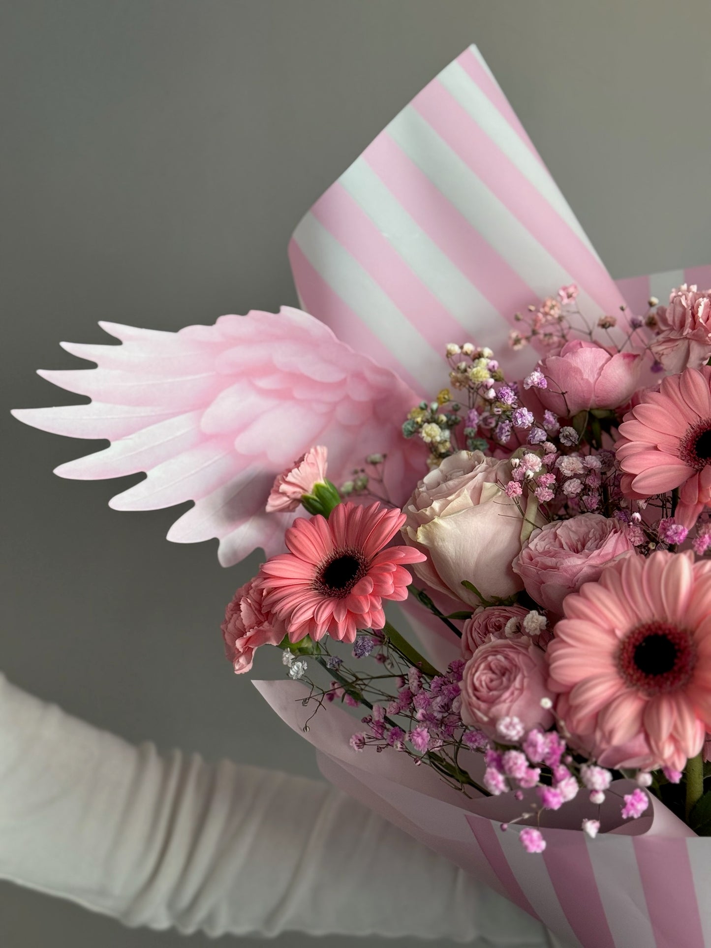 Person holding pink bouquet with butterfly wrapping paper