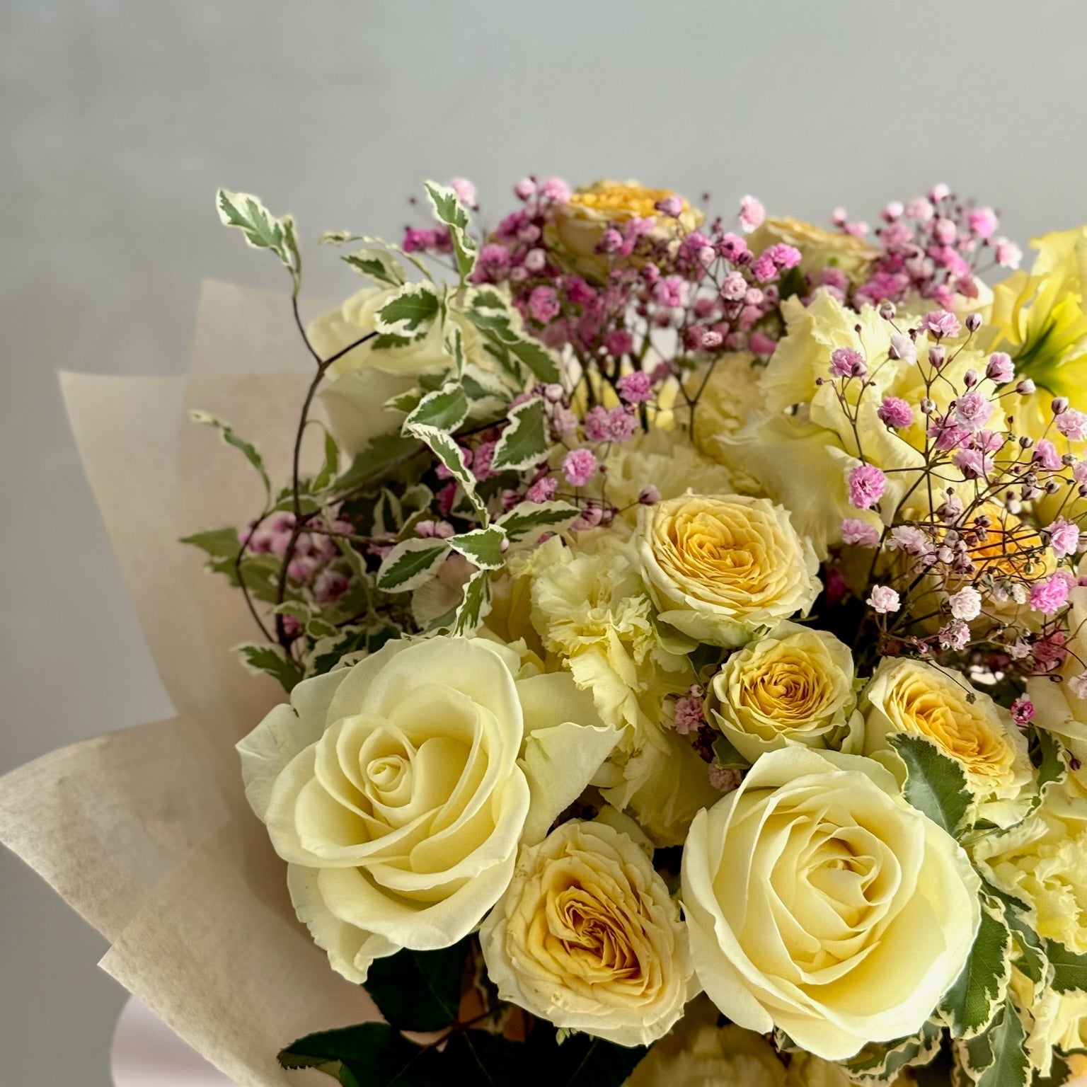 Bouquet of yellow roses and greenery on a light gray background