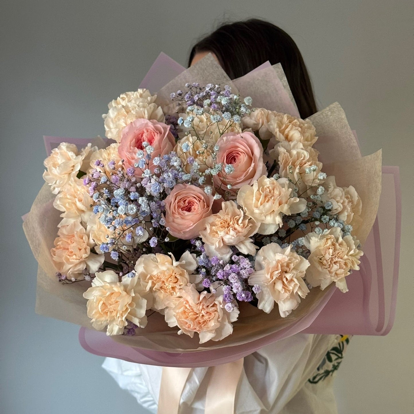 Bouquet of flowers held by a person against a neutral background