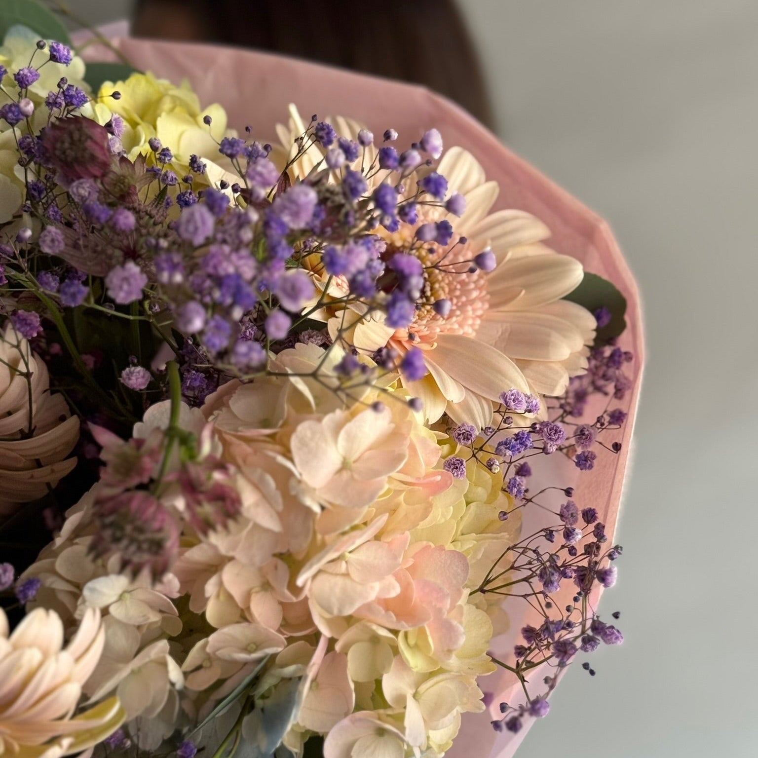 Bouquet of flowers with a pink wrap on a light background