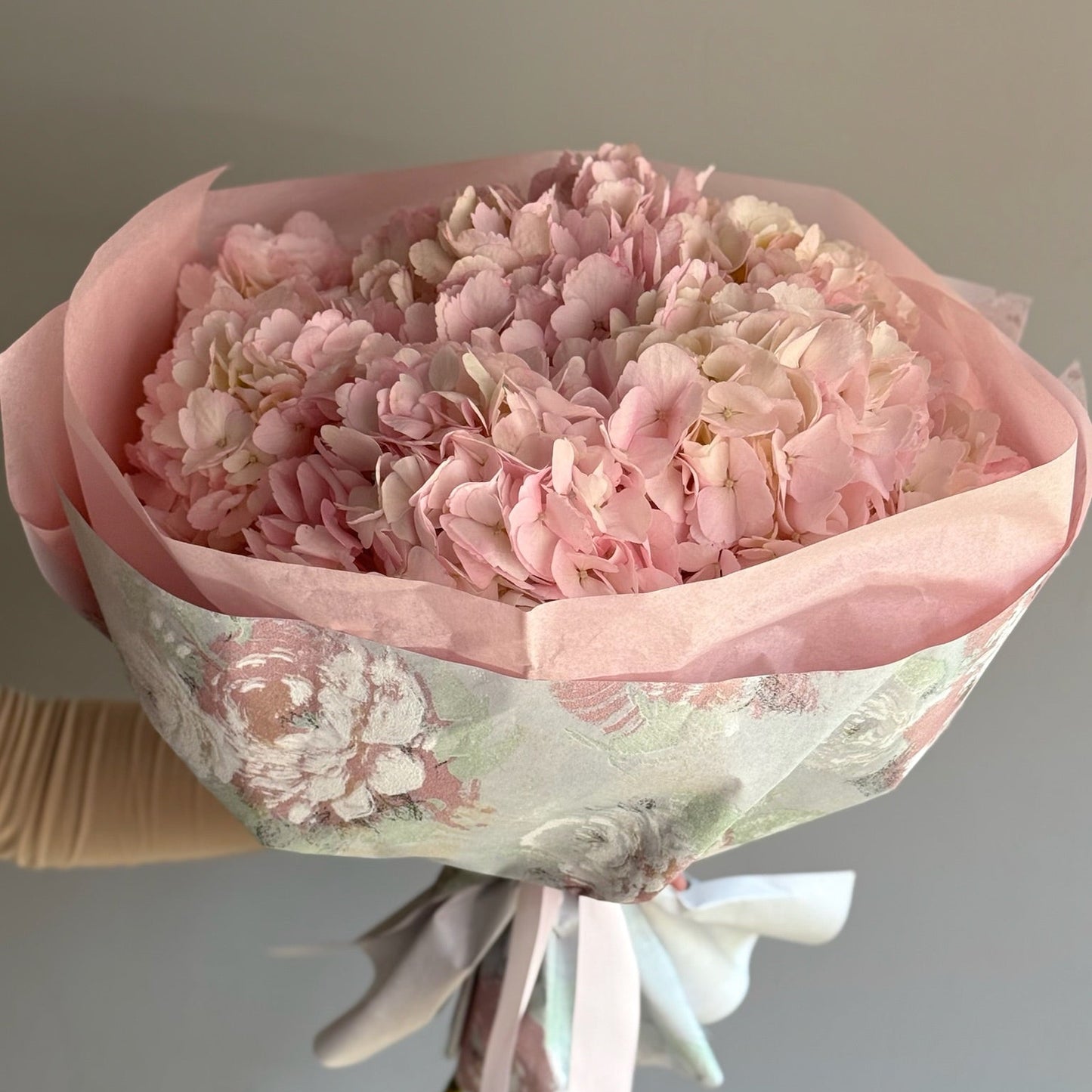 Pink flowers in floral wrapping against a grey background 