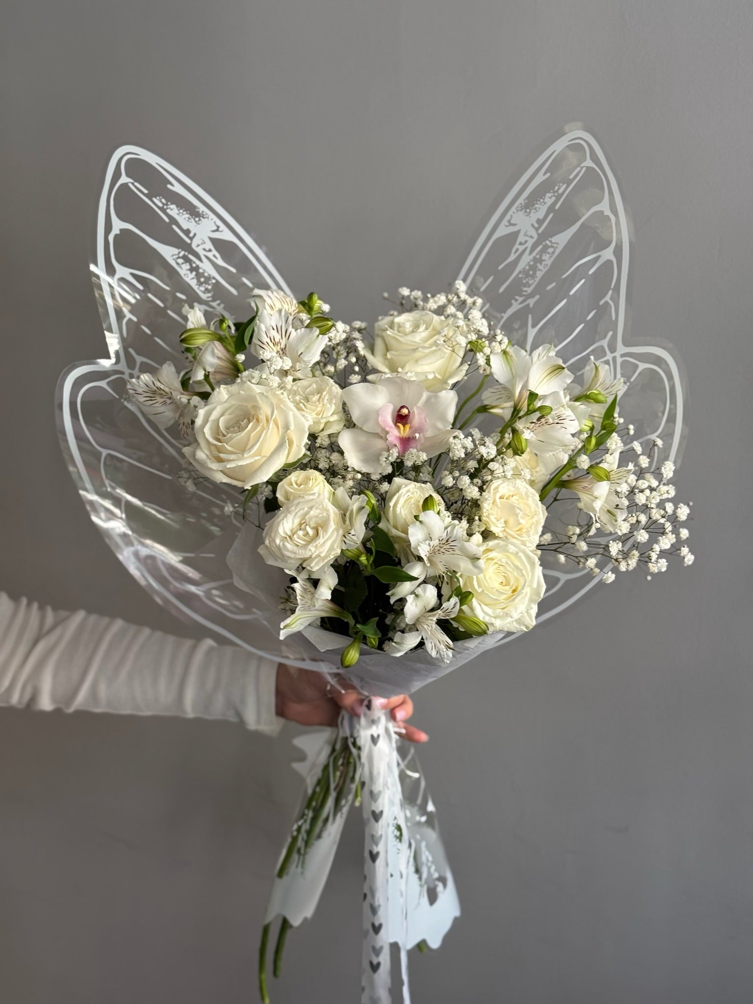 Butterfly bouquet with a mix of white flowerson grey background 