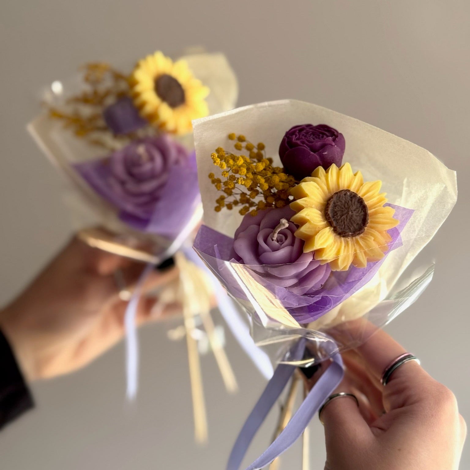 Candle bouquet with sunflower and purple rose at a grey background 