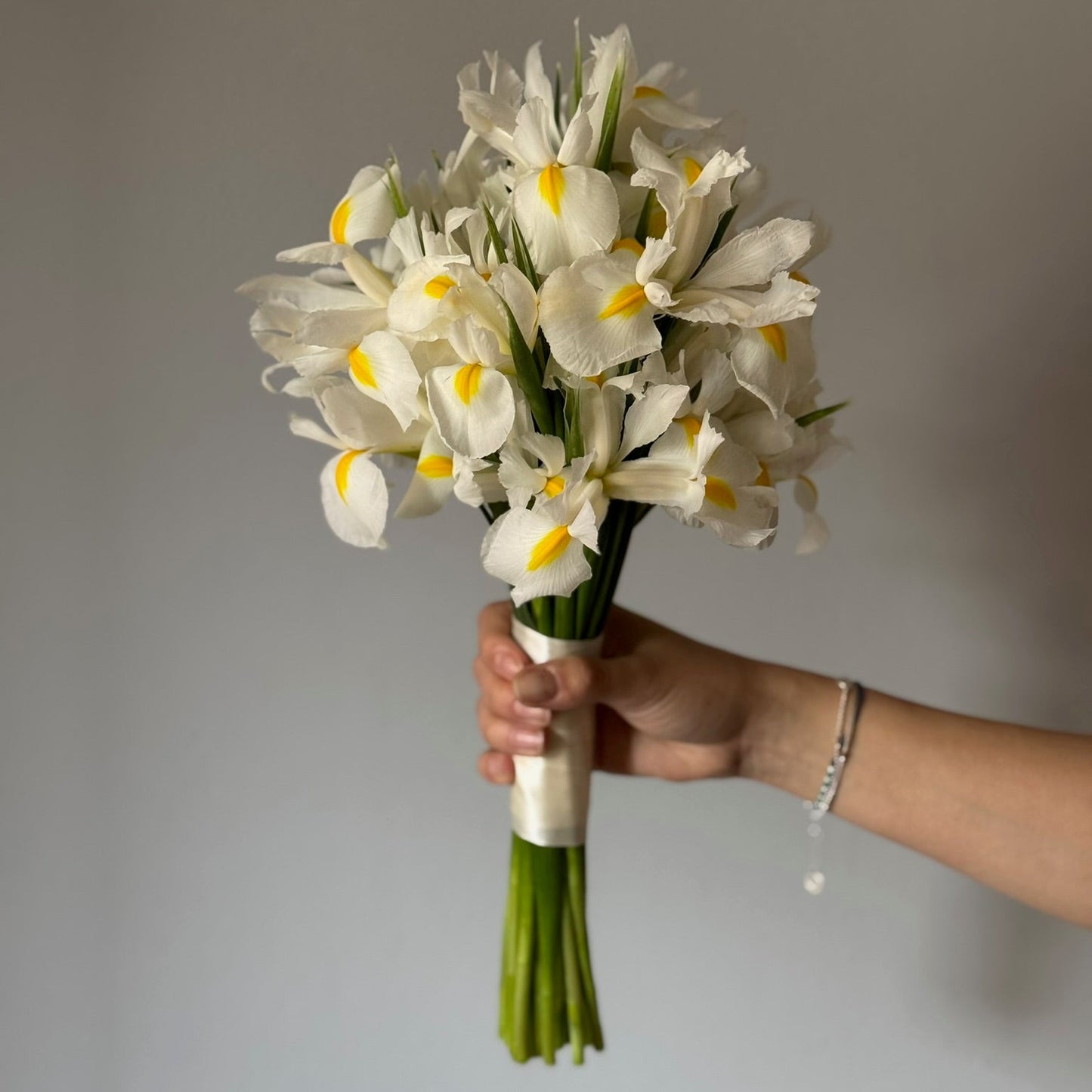 White iris bridal bouquet held on grey background 