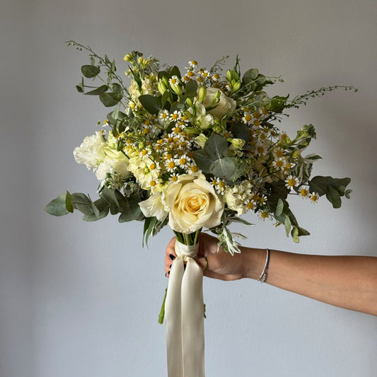 Bouquet of flowers held by a person against a plain background