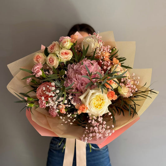 Bouquet of flowers held by a person against a plain background