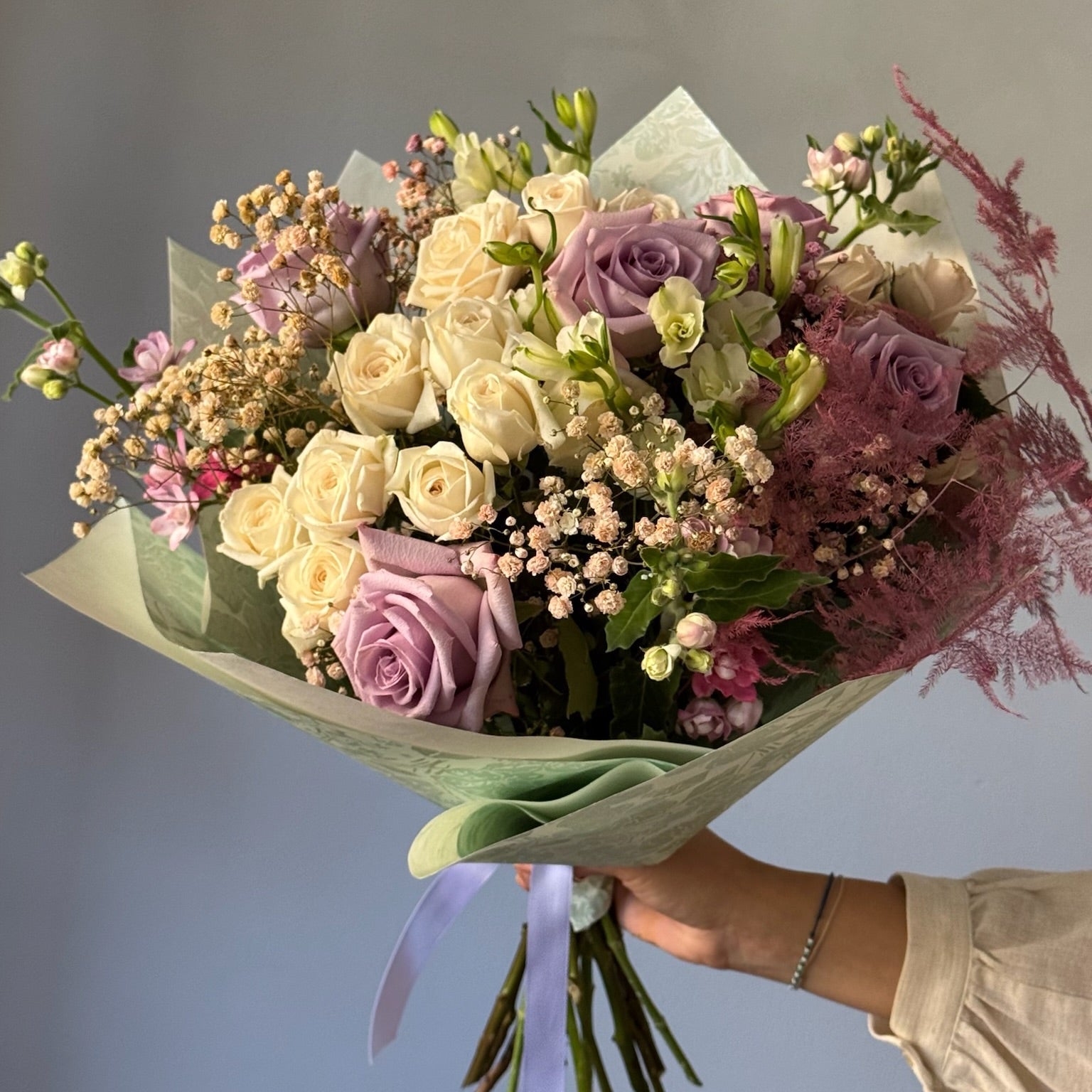 Bouquet of flowers held by a hand against a neutral background