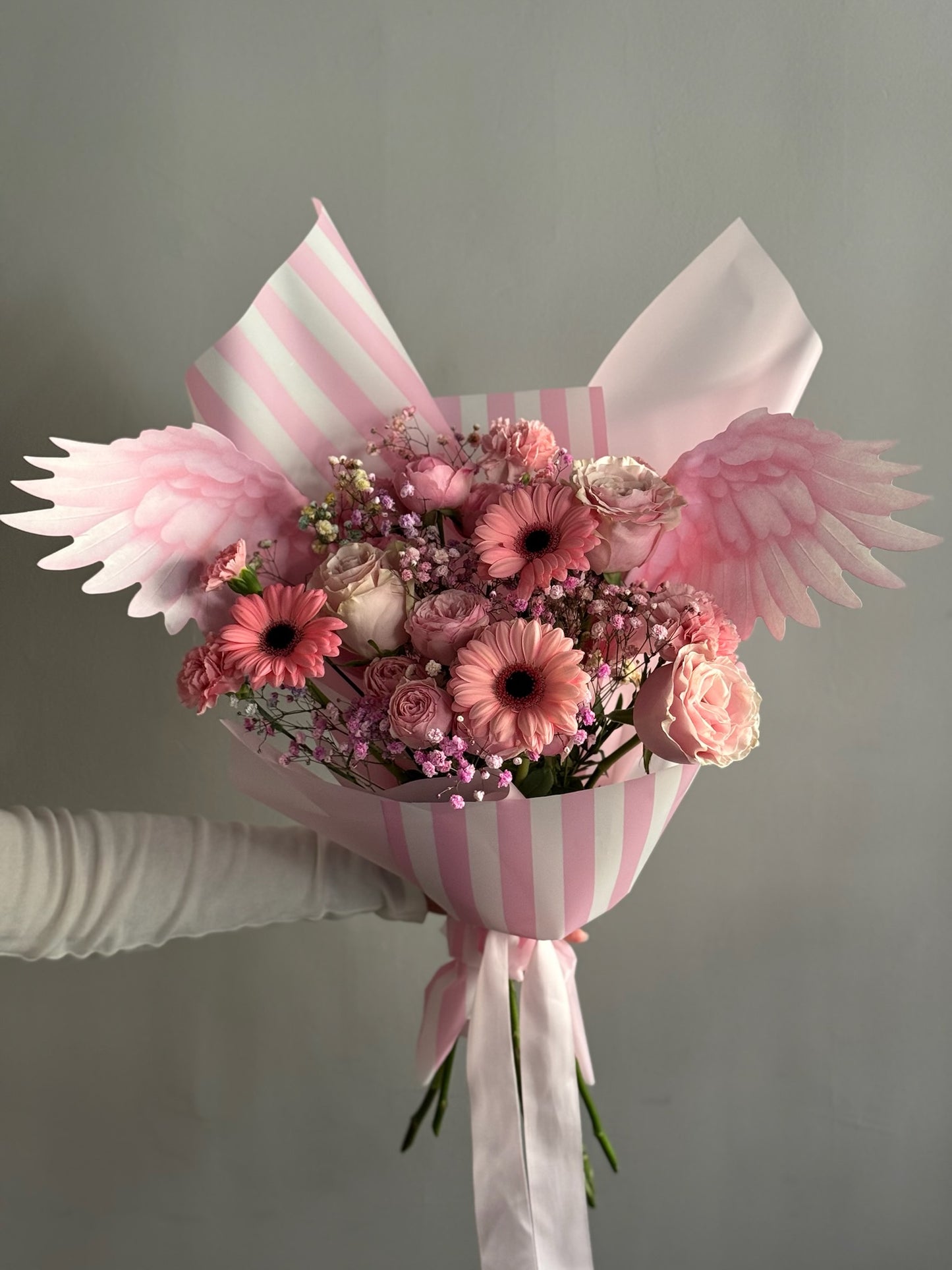 Pink flowers in a big bouquet held on grey background 