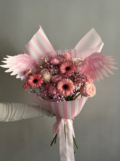 Pink flowers in a big bouquet held on grey background 