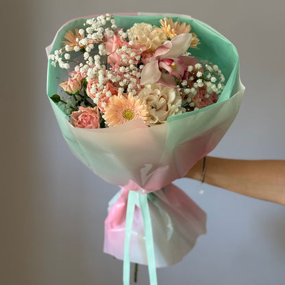 Bouquet with pink and white flowers in wrapping paper on grey background 